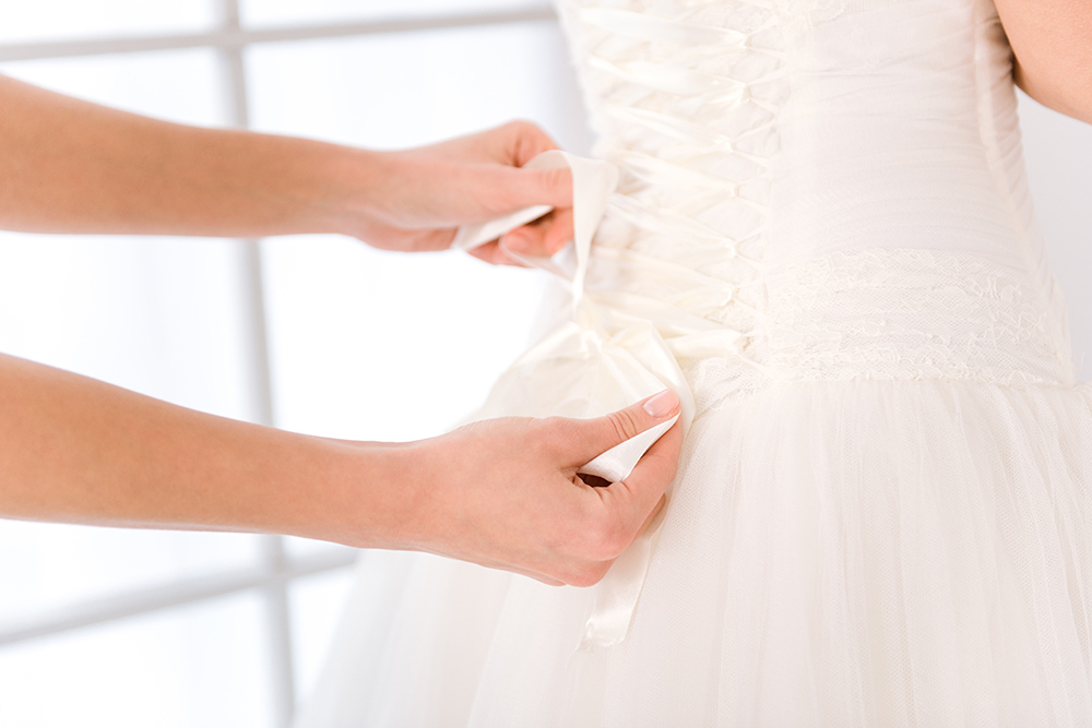 Bride putting white wedding dress